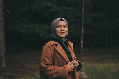 Portrait of smiling young woman standing on field