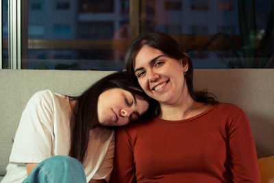 Portrait of young woman sitting on sofa at home