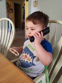 Portrait of cute boy sitting on seat at home