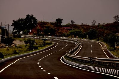 Road amidst trees against sky in city