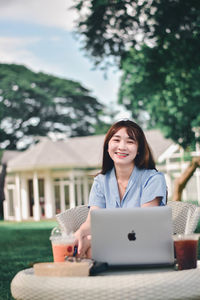 Portrait of a smiling young woman sitting on table