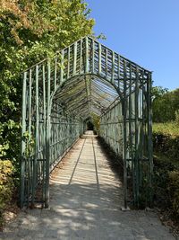 Rose arch amidst trees against sky