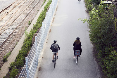 High angle view of commuters riding bicycles on road by fence