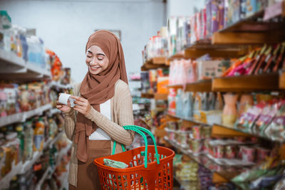 Portrait of young woman standing in supermarket