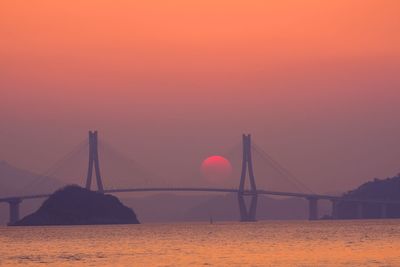 Suspension bridge over sea during sunset