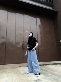 Full length of man wearing mask standing against wall