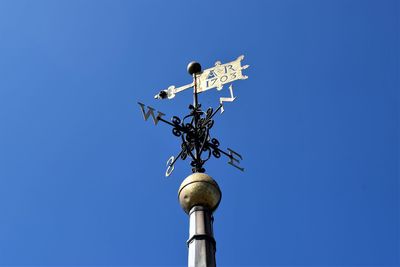 Low angle view of weather vane against clear blue sky