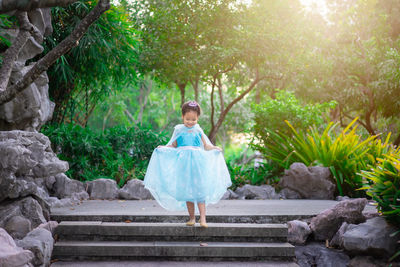 Girl wearing blue dress standing on steps at park