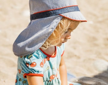 Midsection of girl wearing hat on sand