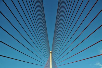 Low angle view of suspension bridge against blue sky