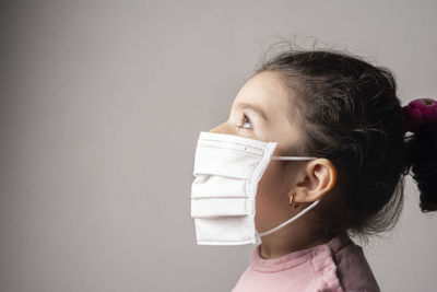 Side view of girl wearing mask against white background