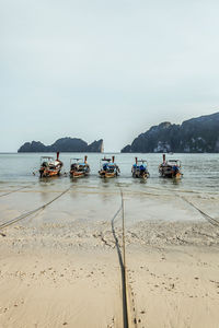 Boats moored on beach against clear sky