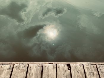 Low angle view of wooden posts in lake against sky