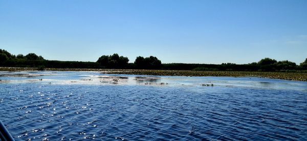 Scenic view of lake against clear blue sky