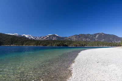 Scenic view of lake and mountains against clear blue sky