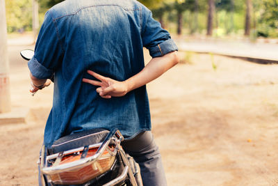 Midsection of man gesturing peace sign while riding motorcycle