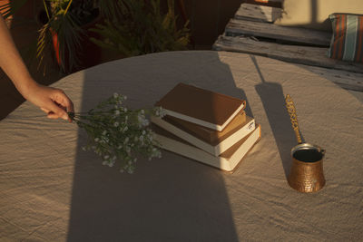 Cropped hand holding flowers on table