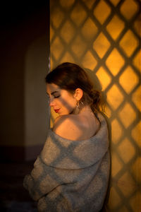 Young woman standing against wall