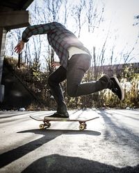 Rear view of woman skateboarding on road