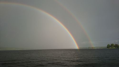 Scenic view of rainbow over sea against sky