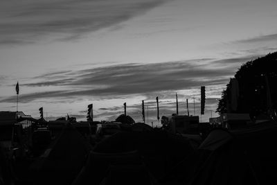 Silhouette buildings against cloudy sky at dusk