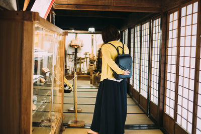 Rear view of woman standing on glass window