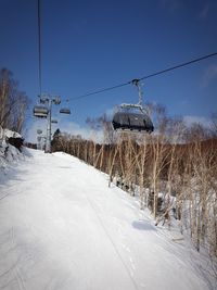 Overhead cable car in snow covered landscape against clear sky