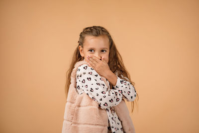 Portrait of young woman standing against yellow background