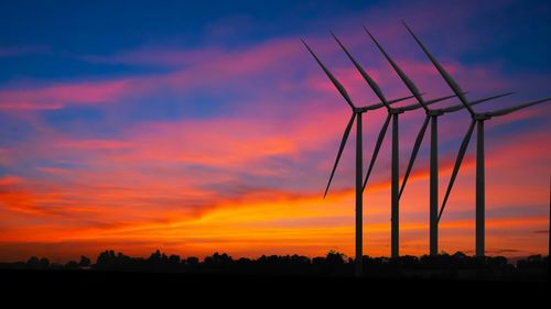 Silhouette electricity pylon on field against romantic sky at sunset