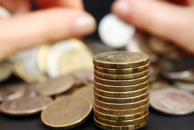 Close-up of hand holding stack of coins on table