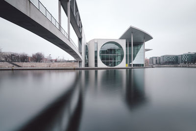 Bridge over river by buildings against sky