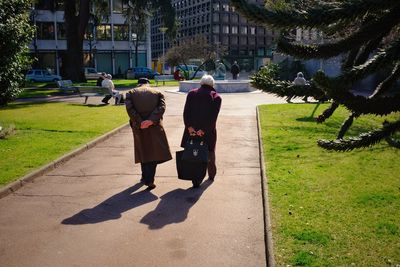 Rear view of friends walking on footpath