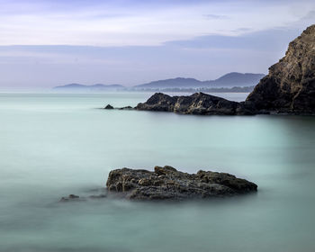 Scenic view of rocks in sea against sky