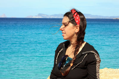 Young woman looking away against sea