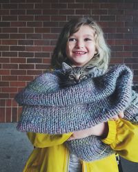 Portrait of smiling girl standing against brick wall