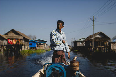 Portrait of man standing in canal against sky