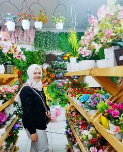 Full length of woman standing by potted plants at store