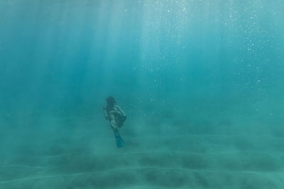 Female free diver swims away in the ocean of oahu, hawaii