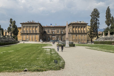 People by historic building against sky