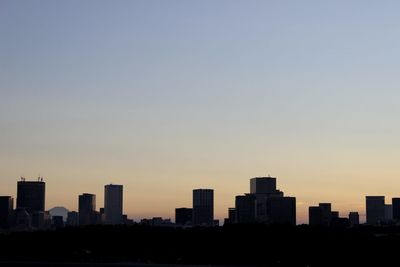 Silhouette buildings against sky during sunset with mt. fuji