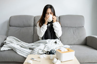 Young woman using mobile phone while sitting on sofa at home