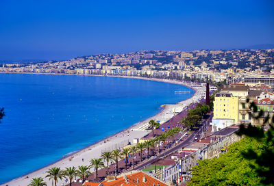 High angle view of buildings by sea against blue sky