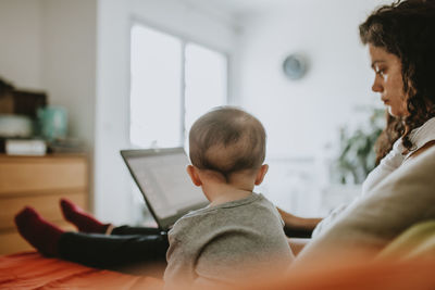 Rear view of mother with baby at working home