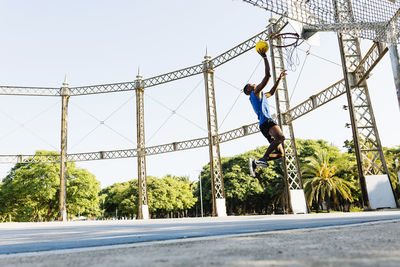 Male basketball player scoring basket at sports court