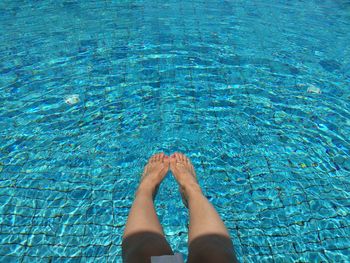 Low section of woman above swimming pool during sunny day