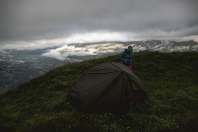 High angle view of woman by tent standing on mountain peak