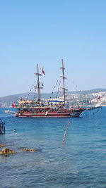 Sailboats moored in sea against clear blue sky