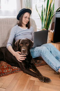 Woman with dog sitting on floor at home