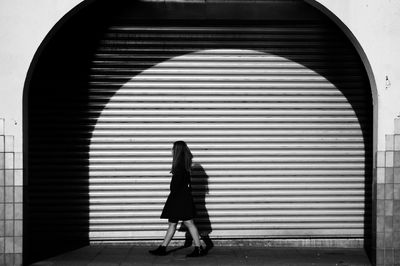 Rear view of woman walking against wall