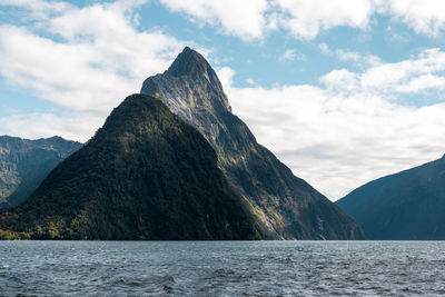 Scenic view of sea by mountains against sky